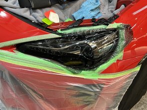 車体を養生してヘッドライトフィルムを施工している様子